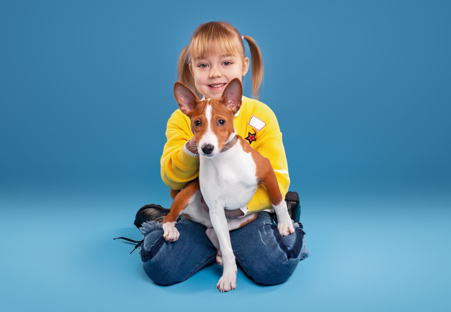 A small girl sitting with a happy dog in her lap during a dog training camp.